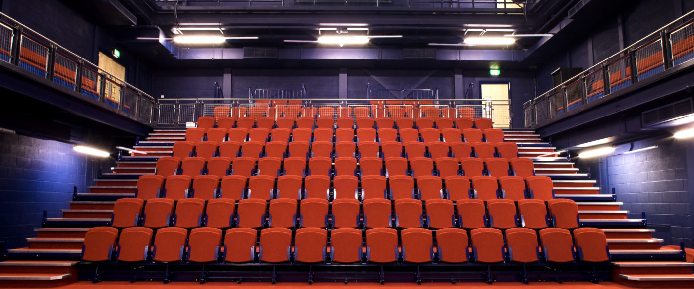 The stage one raked seating taken from the middle of the stage. Steps to the left and right with the main rake in the centre. Two balconies are at the top left and right of the image.
