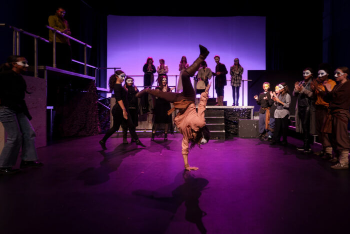 Young person doing a handstand on stage